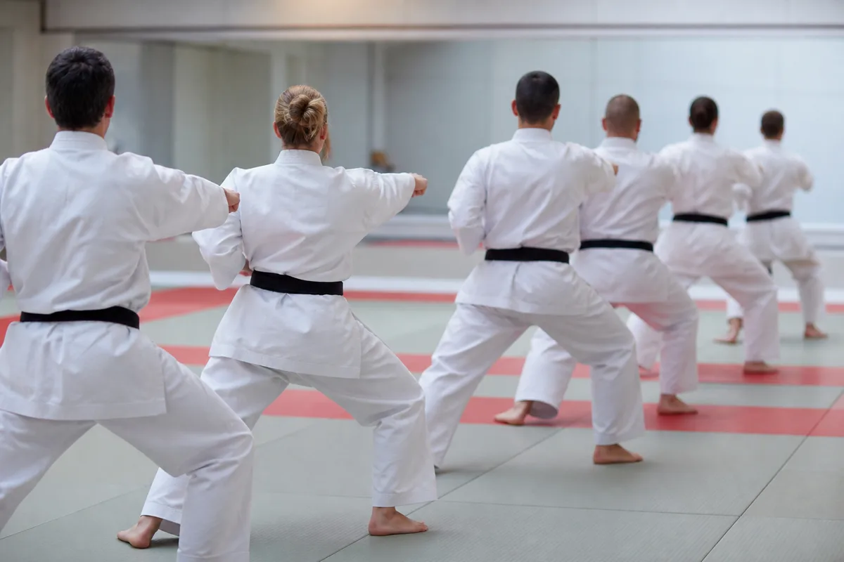 Groupe de pratiquants alignés exécutant un kata dans un dojo